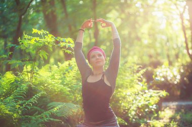 Kadın gün batımında yoga pozisyonunda duruyor. Güneş ışığı sisi. Yoga Mudra 'sında eller havaya..