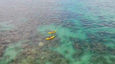 4K İHA görüntüleri, Lanikai Sahil Parkı, Oahu, Hawaii, ABD 'de kristal berrak su mercan resifi ile kıyı şeridinde kayak yapan iki kano görüntüsü..