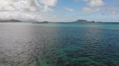 4K insansız hava aracı mercan resifinin kıyı şeridinde kristal berrak su ve arka Lanikai plaj parkında küçük adalar, Oahu, Hawaii, ABD açılı 4K görüntüsü..