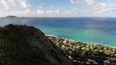 Lanikai Pillbox, Oahu, Hawaii, ABD 'deki sahil, palmiye ağaçları ve köylü turkuaz deniz manzaralı 4K drone görüntüleri. Düşük açı, seyahat ve parallax hareketi..