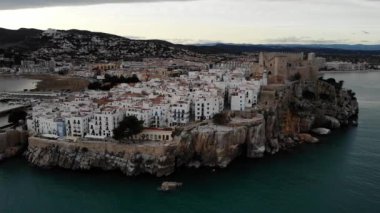 Peiscola, Castelln, Spain.Orta açı, parallax hareket alanındaki uçurum kıyısındaki eski kasaba ve kale üzerinde 4K gün batımı drone görüntüleri.