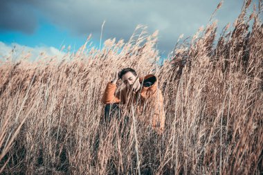 Tarlada oturan beyaz bir adam. Sarı örtülü ceket. Güneşli bir gün