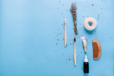 Ahşap kaşık, fırça ve lavanta ile mavi arka planda izole edilmiş gerekli yağ şişesi