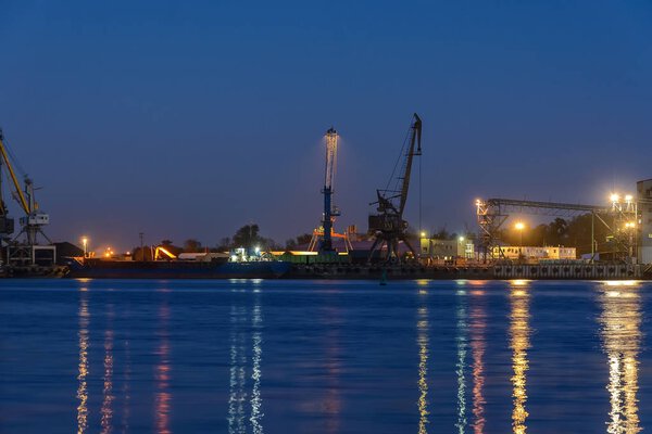 Commercial docks at night with a ship and cranes