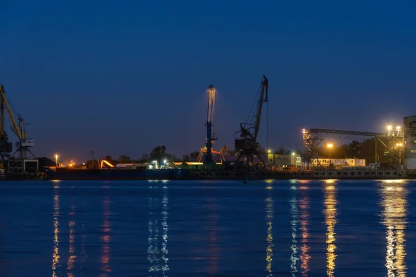 Commercial docks at night with a ship and cranes Stock Picture