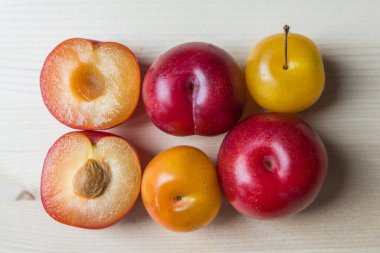 Beyaz kesme tahtasındaki sarı erikler ve kırmızı erikler