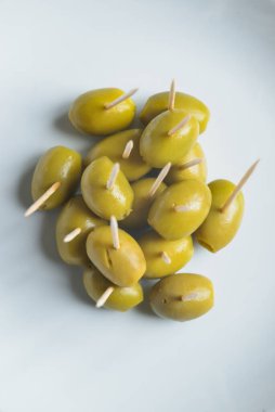 Beyaz tabakta kürdanlı yeşil zeytin.