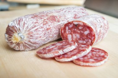 Tahta kesme tahtasında dilimlenmiş salam.