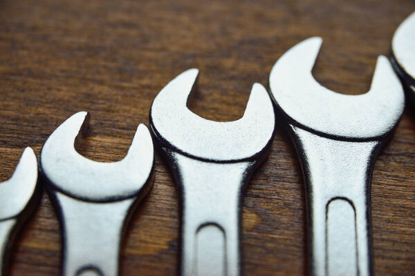 Metallic wrenches on wooden surface