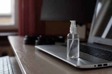El dezenfektanı antiseptiği laptopta. Evde çalışmak, kendini soyutlama konsepti..