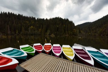 Colorful boats near the pier on the Red Lake in Transylvania, Romania in autumn. clipart