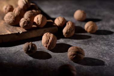 Tahtadaki cevizler koyu bir arka planda duruyor. Sert ışıkta seçici odak.