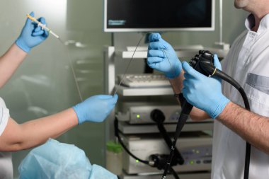 Hastanedeki bir hastanın endoskopik muayenesi. Doktor ve hemşire ellerinde gastroskopi aleti tutuyorlar.