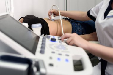 Kadın bir hastanın karın boşluğunda ultrason muayenesi. Doktor klinikte modern ultrason makinesiyle çalışıyor.