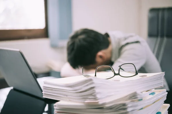 İş adamı, elinde hesap makinesiyle ofis masasında uyuyor. Kötü bir baş ağrısı, stres ve aşırı çalışma konsepti yaşıyor..