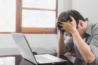 İşadamı ofiste dizüstü bilgisayarla çalışırken strese girdi, yorgun Asyalı adam kafasına dokundu, kötü bir baş ağrısı, stres ve aşırı çalışma konsepti yaşıyor..