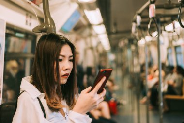 Metroda akıllı telefon kullanan bir iş kadını trenle seyahat ederken akıllı telefon üzerinde çalışan bir kadın. İş seyahati kavramı.