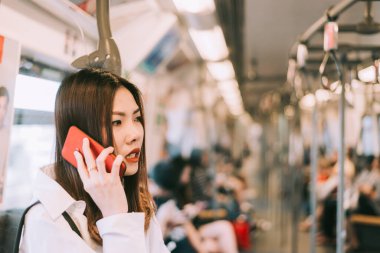 Metroda akıllı telefon kullanan bir iş kadını trenle seyahat ederken akıllı telefon üzerinde çalışan bir kadın. İş seyahati kavramı.