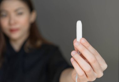 Elinde regl tamponu olan bir kadın, adet tamponu. Adet zamanı. Hijyen ve koruma.