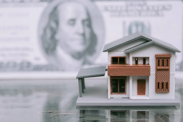 Miniature house toy with money as background.Mortgage concepts.
