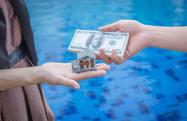 Miniature house toy and money in man's hands.Mortgage concepts.
