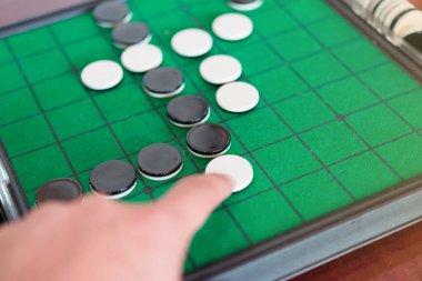 Yeşil Reversi tahtasında (Othello) yakın çekim diskleri, strateji iş konsepti.
