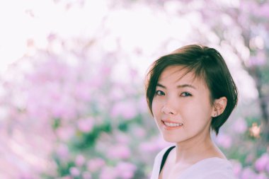 Çiçek açan kiraz çiçekleriyle gülümseyen güzel bir genç kadın..