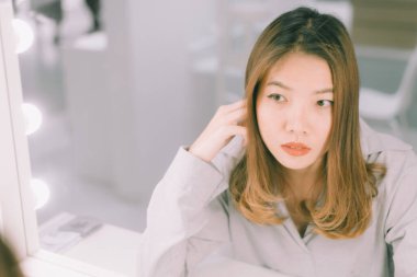 Genç Asyalı kadın aynada kendine bakıyor..