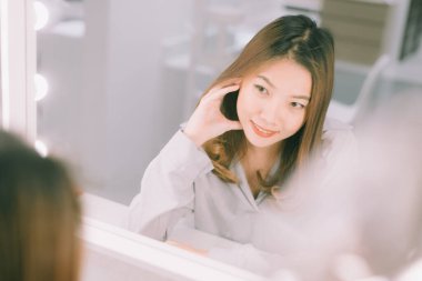 Genç Asyalı kadın aynada kendine bakıyor..