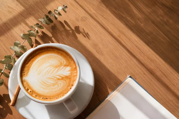 Bir fincan sıcak latte sanat kahvesi, ahşap masada, kafede kitap..