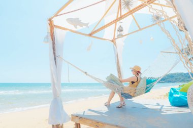 Kumsalda hamakta dinlenen kadın, yaz tatili ve seyahat konsepti.