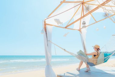 Kumsalda hamakta dinlenen kadın, yaz tatili ve seyahat konsepti.