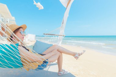 Kumsalda hamakta dinlenen kadın, yaz tatili ve seyahat konsepti.