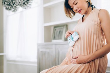 24 haftalık hamile kadın oturma odasındaki pencerenin yanında dinleniyor.