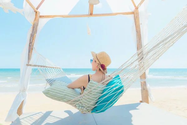 Kumsalda hamakta dinlenen kadın, yaz tatili ve seyahat konsepti.
