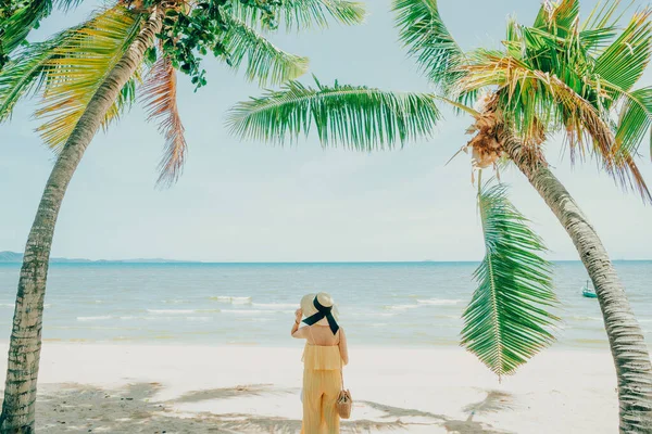 Plajda keyif çatan bir kadın tropik mavi sularda keyif çatıyor. Plaj şapkası takan bir model..