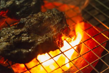 Izgarada ızgara domuz pirzolası ve alevler.