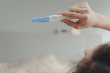 Genç Asyalı kadın hamilelik testine bakıyor. Hamilelik aile konsepti.