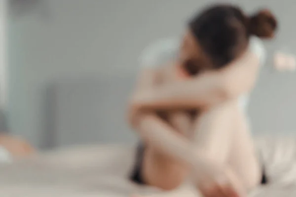 Blurred sad woman sitting alone in a bedroom