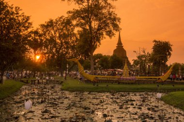 Tayland 'ın Provinz Sukhothai kentindeki Sukhothai' de bulunan tarihi parktaki Loy Krathong Festivali 'nde bir tekne ve tapınak. Tayland, Sukhothai, Kasım 2019