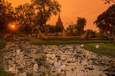 Tayland 'ın Provinz Sukhothai kentindeki Sukhothai' de bulunan tarihi parktaki Loy Krathong Festivali 'nde bir tekne ve tapınak. Tayland, Sukhothai, Kasım 2019