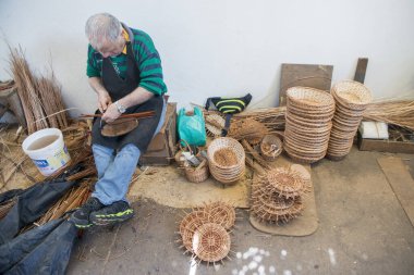 Portekiz 'in Madeira Adası' ndaki Madeira Adası 'nın doğusundaki Camacha kasabasındaki Arema Kafe Relogio Reklam Dükkanı' nda sepet dokuma işi. Portekiz, Madeira, Nisan 2018