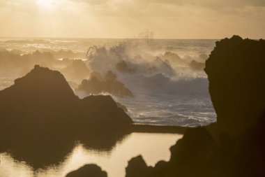 Portekiz 'in Atlantik Okyanusu' ndaki Madeira Adası 'ndaki Porto Moniz kasabasında gün batımında dalgalar ve rüzgar. Madeira, Porto Moniz, Nisan 2018