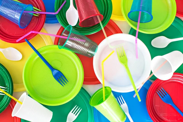Parlak renkli tek kullanımlık plastik sofra takımı arka planı. Piknik seti. Ekoloji problemi. Üst görünüm.