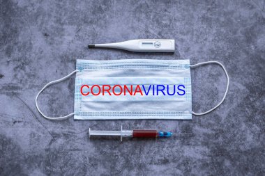 Solunum korumalı tıbbi maske, termometre ve üzerinde kan örnekleri olan tek kullanımlık şırınga. Romanlar hızla yayılan Coronavirüs, COVID-19 salgını. Düz yatış, üst görünüm.