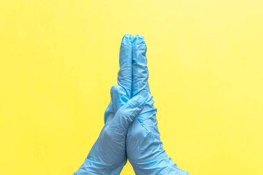 Sarı arka planda tek kullanımlık nitril eldivenli kadın elleri. Koronavirüs koruması kavramı, COVID-19 salgını, küresel karantina.