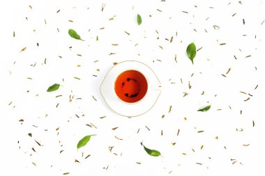 Seramik çay, taze yeşil yapraklar ve beyaz arka plana saçılmış kurumuş bitkiler. Sabah çay seremonisi kavramı. Düz kompozisyon. Yaratıcı yerleşim.