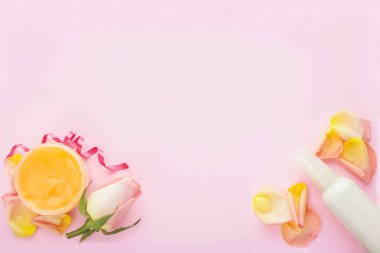 Açık kozmetik krem kavanozu, beyaz kozmetik şişesi, pembe arka planda gül ve gül yaprakları. Doğal spa kozmetik kavramı. Düz konum, üst görünüm, kopyalama alanı.