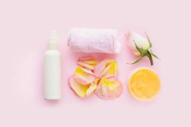Kozmetik krem kavanozu, beyaz kozmetik şişesi, havlu ve pembe arka planda gül. Doğal spa kozmetik kavramı. Düz konum, üst görünüm, kopyalama alanı.