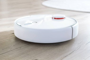 Plastik zeminde beyaz robot elektrikli süpürge. Modern akıllı aygıt temizleme tabanı.